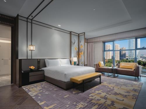a bedroom with a bed and a couch and a window at HUALUXE Kunshan Huaqiao by IHG - F1 Racing Preferred Hotel in Kunshan