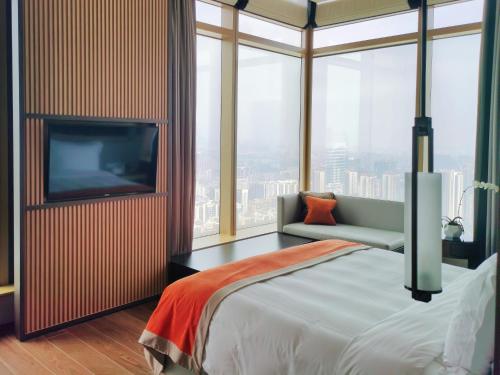 a bedroom with a bed and a tv and windows at Jumeirah Guangzhou - Complimentary Shuttle Bus to Canton Fair Complex in Guangzhou