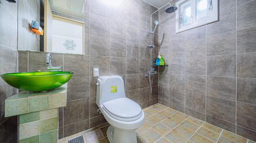łazienka z toaletą i zieloną umywalką w obiekcie Geojerowa Pension w mieście Geoje