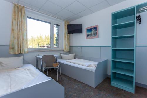 a room with two beds and a desk and a window at Sportpark Rabenberg in Breitenbrunn