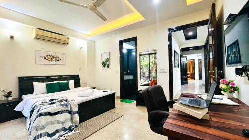 a bedroom with a bed and a desk with a laptop at BluO Park Facing 3BHK- Lift, Balcony, Parking in New Delhi