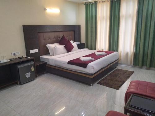 a hotel room with a large bed and a desk at Vella Mrina Group of Hotel Edge # Free Parking-cricket stadium 10 km-Mcleodganj 2 km- Bhagsunag 4 km in Dharamshala