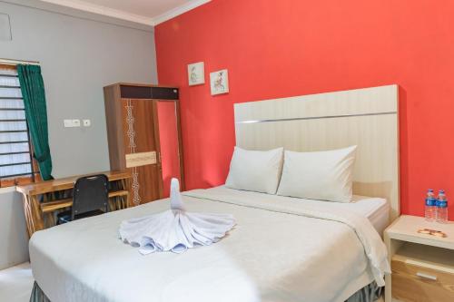 a bedroom with a white bed with a red wall at Metro Malioboro Living in Yogyakarta