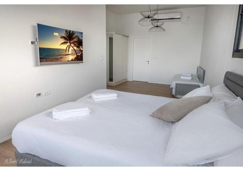 a white bedroom with two beds and a picture on the wall at Dream House Tiberias in Tiberias