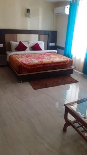 a bedroom with a large bed with red pillows at Nadi Mountain view Hotel in Dharamshala