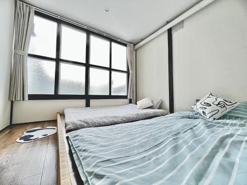 a bedroom with two beds and a large window at attomi hostel in Sapporo