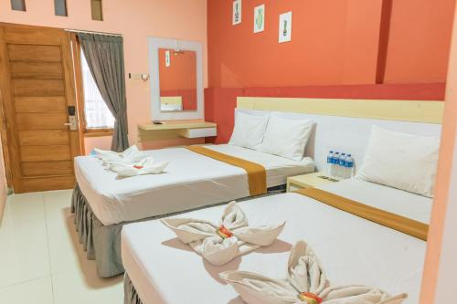 a hotel room with two beds with flowers on them at Metro Malioboro Living in Yogyakarta