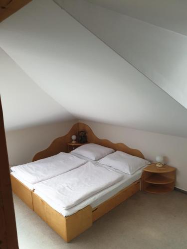 a bed with white sheets and a wooden headboard in a room at Hotel Zámeček na Čeladné in Čeladná