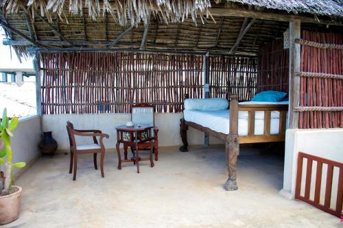 Cette chambre comprend un lit, une table et des chaises. dans l'établissement LAMU HOUSE, à Lamu