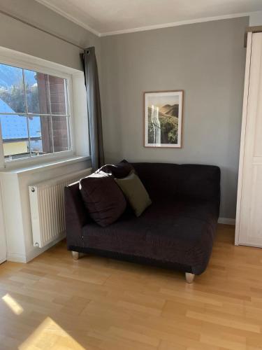 a living room with a black couch and a window at S´Kraftplatzl in Bad Aussee