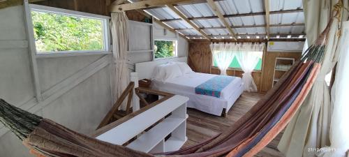 a room with a hammock and a bed and two windows at Hotel YELLOW HOME Providencia Isla in Providencia