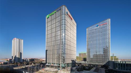 two tall glass skyscrapers in a city at Holiday Inn Express Qingdao Northern West Coast by IHG in Qingdao