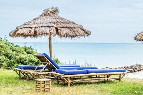 two lounge chairs and an umbrella on the beach at First Camp Bøsøre Strand Feriepark in Hesselager