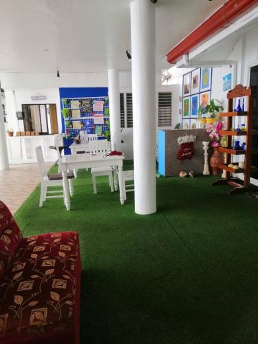 a living room with a green carpet and a table and chairs at Germaroze in Oslob