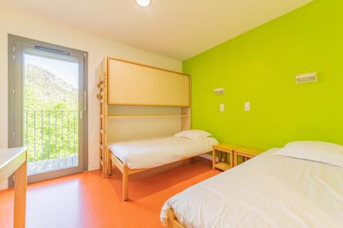 Duas camas num quarto com paredes verdes e uma janela em LA FONTAINE D'ANNIBAL em Buis-les-Baronnies