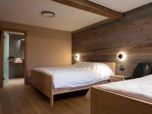 a bedroom with two beds and a wooden wall at La Maison du Notaire in Houffalize