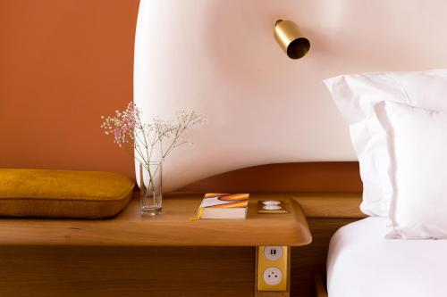 a vase of flowers on a table next to a bed at Les Terrasses du Bailli in Rayol-Canadel-sur-Mer