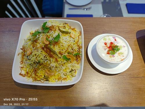 a plate of noodles and a bowl of rice on a table at Hotel Red Chillee Restro in Silvassa