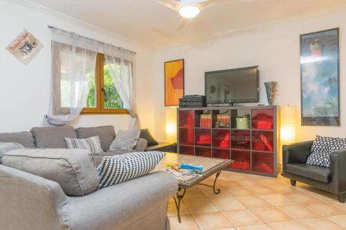 ein Wohnzimmer mit einem Sofa und einem TV in der Unterkunft Villa Ewa by Slow Villas in Cala Pi