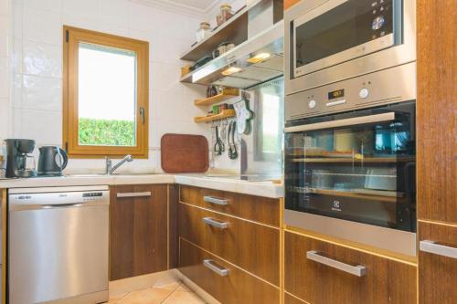 eine Küche mit Holzschränken, einem Waschbecken und einem Fenster in der Unterkunft Villa Ewa by Slow Villas in Cala Pi