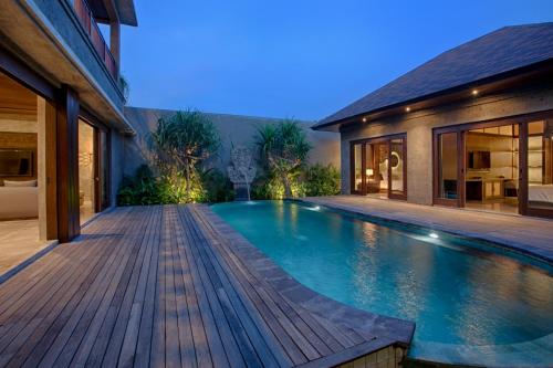 a swimming pool in a house with a wooden deck at Taman Dharmawangsa Suites in Nusa Dua