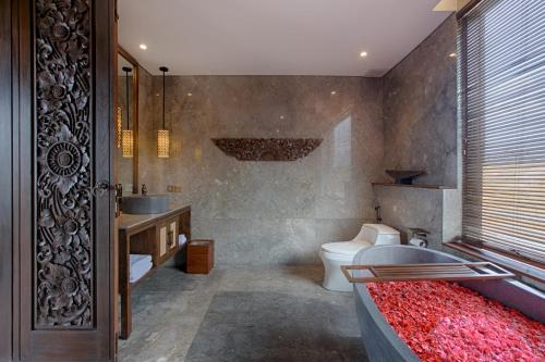 a bathroom with a toilet and a sink and a tub at Taman Dharmawangsa Suites in Nusa Dua