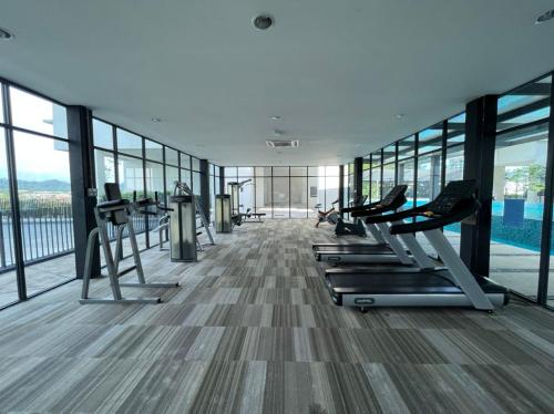 a gym with cardio equipment in a building with windows at Apartment with 2 Bedrooms, Trefoil @ Setia City (Imperia Asia Guest House) in Shah Alam
