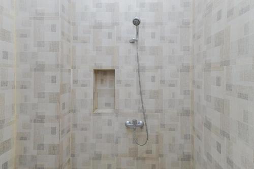 a shower with a shower head in a bathroom at RedDoorz at Ngaggel Jaya Surabaya in Surabaya