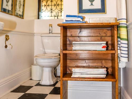 a bathroom with a toilet and a shelf with books at Backworth House in Mid Illovo