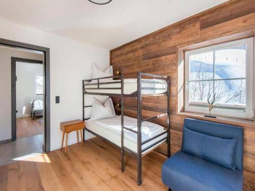a bedroom with bunk beds and a blue chair at Leni`s Mountain Appartements in Dienten am Hochkönig