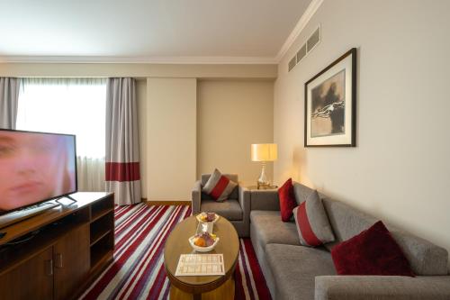 a living room with a couch and a tv at Wonder Palace Hotel Qatar in Doha