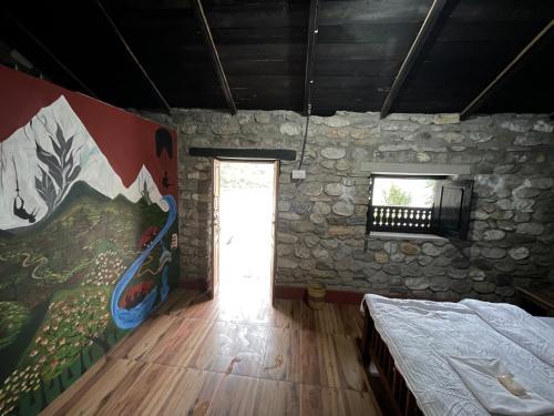 a bedroom with a painting on the wall and a window at River Edge Resort Nepal in Benighāt