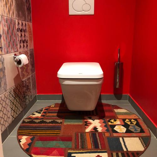 - une salle de bains rouge avec toilettes et tapis dans l'établissement Beau studio Bastille, à Paris