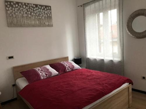 um quarto com uma cama com lençóis vermelhos e uma janela em Apartments Colors of Rijeka - Red em Rijeka