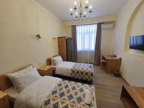 a hotel room with two beds and a chandelier at Chorsu Inn in Tashkent