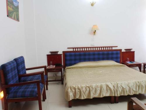 ein Schlafzimmer mit einem Bett mit einem blauen Kopfteil und einem Stuhl in der Unterkunft GMVN Guest House Rudraprayag in Kurchhola