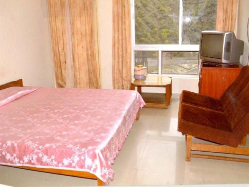 Schlafzimmer mit einem Bett, einem TV und einem Stuhl in der Unterkunft GMVN Guest House Rudraprayag in Kurchhola