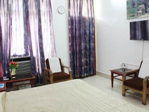 Schlafzimmer mit einem Bett, Stühlen und Vorhängen in der Unterkunft GMVN Guest House Rudraprayag in Kurchhola