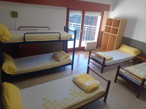 a room with three bunk beds and a balcony at Planoles Xanascat in Planoles