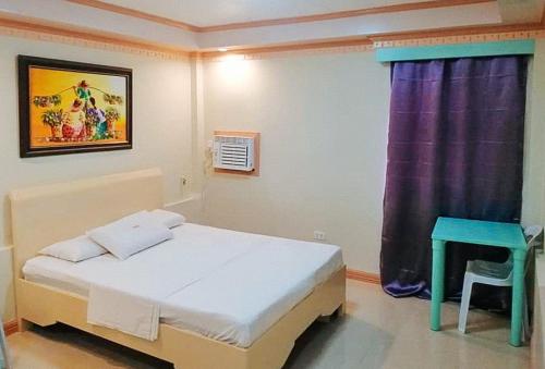 Dormitorio pequeño con cama y mesa en IDMAT INN en Davao