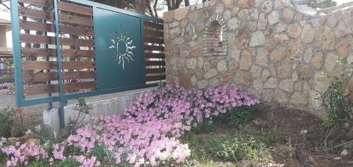 a wall with purple flowers next to a stone wall at Armiriki Apartments in Korakokhórion