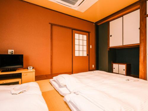 a bedroom with two beds and a flat screen tv at Hotel AreaOne Takamatsu in Takamatsu