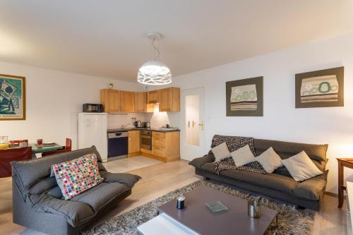 un salon avec deux canapés et une cuisine dans l'établissement Le Bonnet Rouge - Appartement 2 chambres avec parking, à Rennes