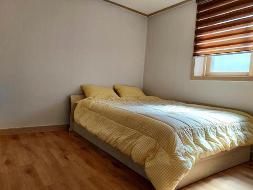 a bedroom with a bed with yellow pillows and a window at Lakeside Mirinae Villa in Anseong