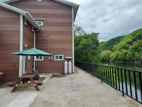 a picnic table with an umbrella on the side of a building at 미리내 호숫가 독채펜션 in Anseong