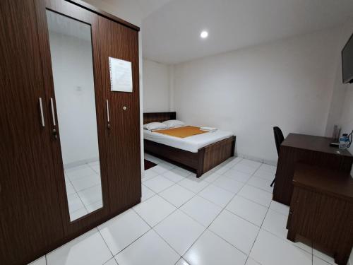 a small room with a bed and a mirror at Pillow Guest House in Balikpapan