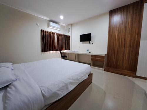 um quarto com uma cama, um lavatório e uma secretária em Pillow Guest House em Balikpapan