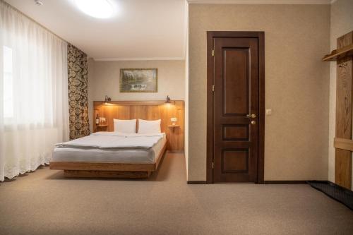 a bedroom with a bed and a wooden door at Private Rooms in Hotel 3 поверх in Bukovel