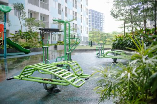 Kia Servised Apartmen at Grand Sentraland Karawang في كراوانغ: مجموعة من معدات الملعب الخضراء في الحديقة