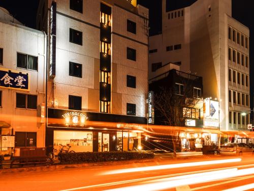 a city street at night with buildings and lights at Hotel AreaOne Takamatsu in Takamatsu